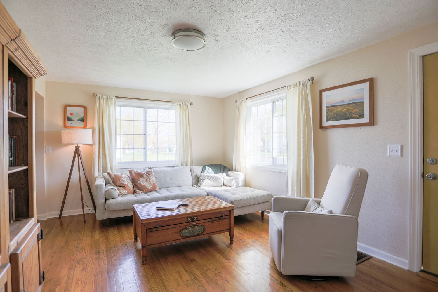 A cozy and well-lit living room with a comfortable sofa, coffee table, and framed artwork on the walls.
