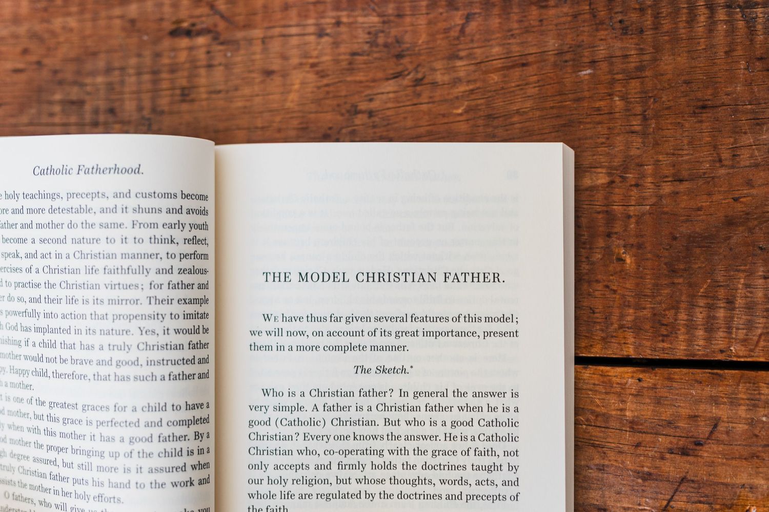 An open book with text pages displayed on a rustic wooden table surface.
