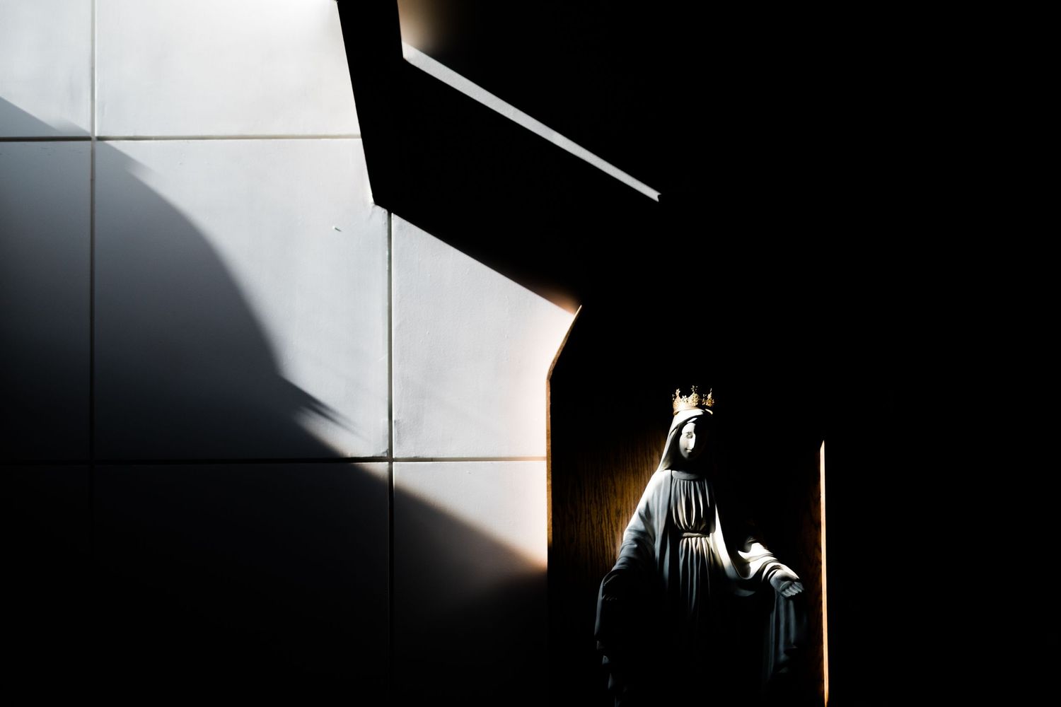 Dramatic shadows and light creating geometric patterns on a dark wall.