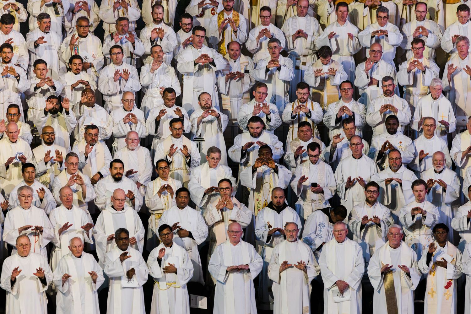A large group of chefs in white uniforms and hats pose together for a professional group photo.