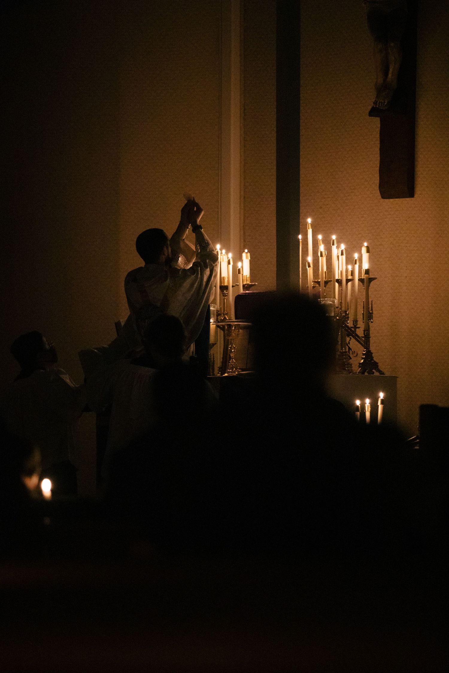Candlelit religious service creating silhouettes against a dark background.