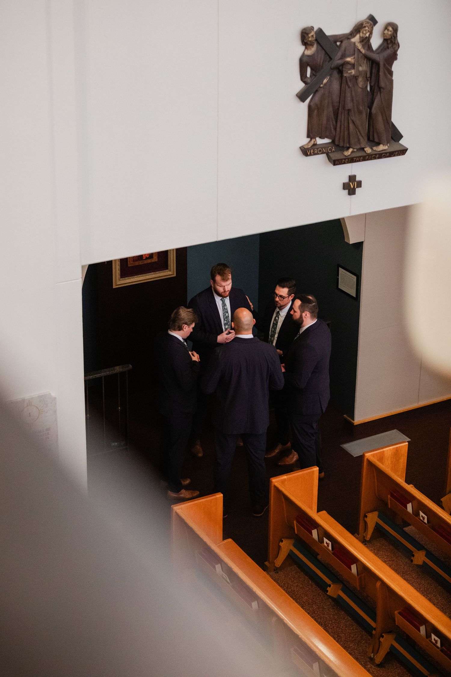 A series of photos showing people in dark suits walking through wooden church pews in a dimly lit interior space.