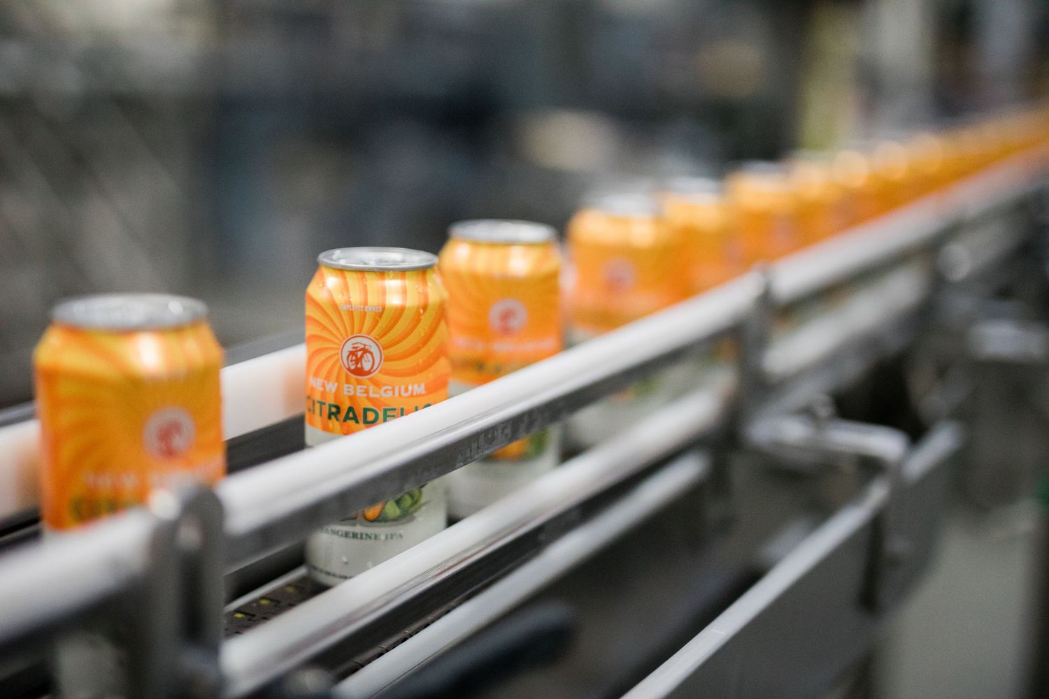 Orange Starbucks drinks move along a curved industrial production line conveyor belt.