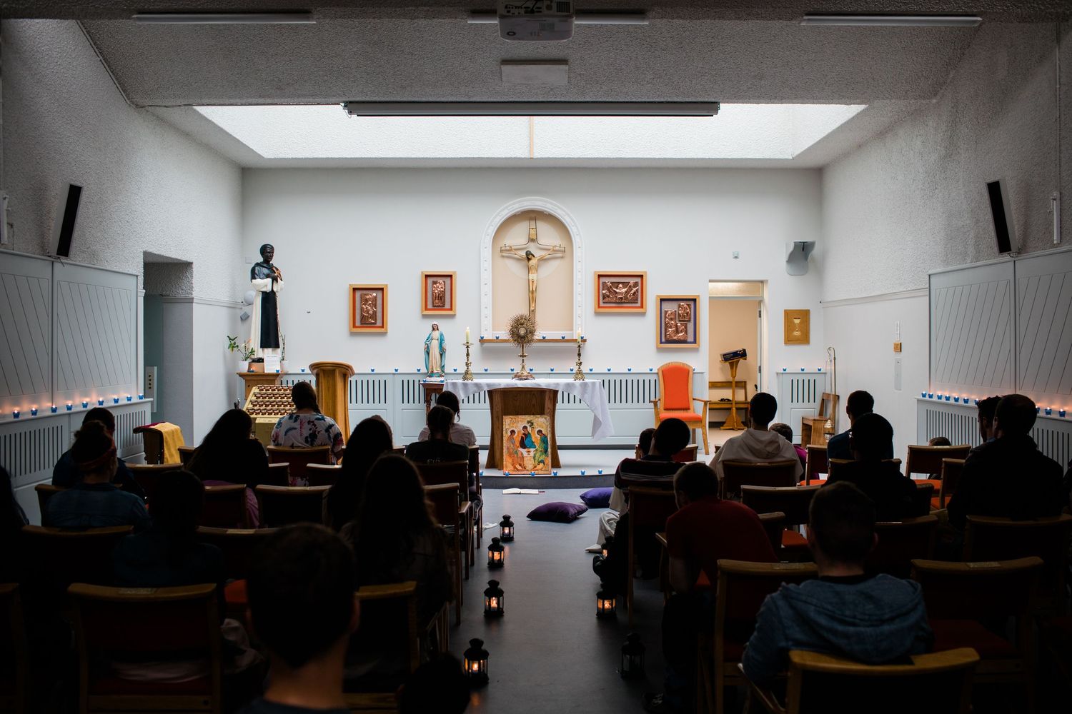 People seated in pews during a Catholic church service with an altar and crucifix at the front.