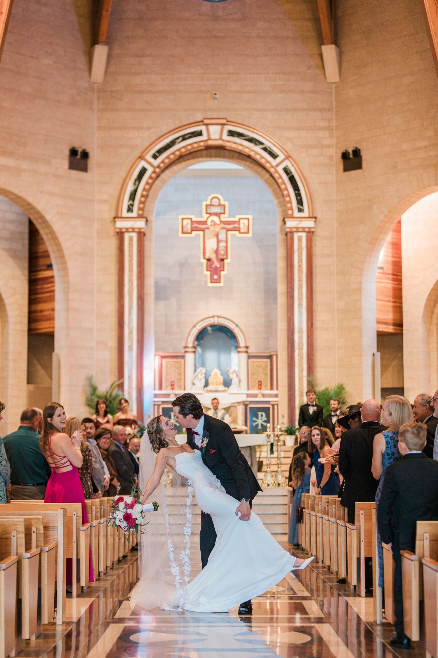 Bride and groom share a romantic dip kiss at the altar of an elegant church during their wedding ceremony.