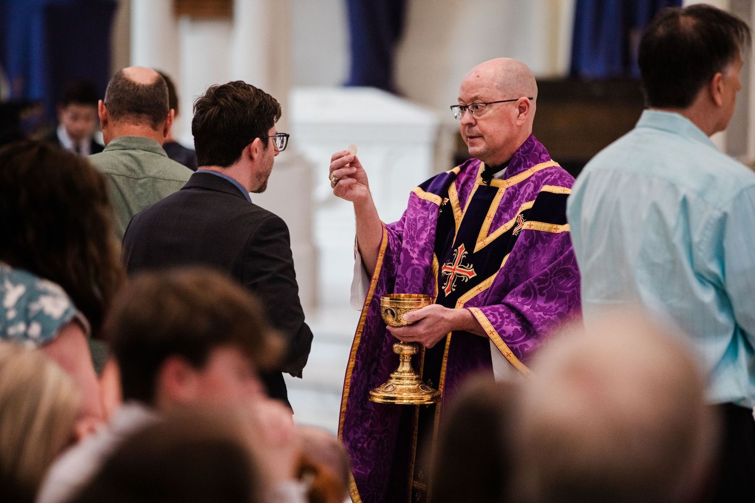 Close-up view of clergy members in purple vestments during a religious service in an ornate church setting.