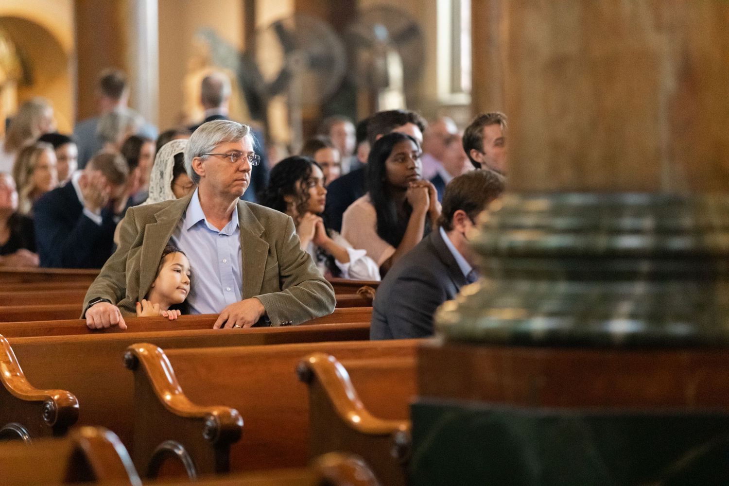 Church congregation seated in wooden pews during service.