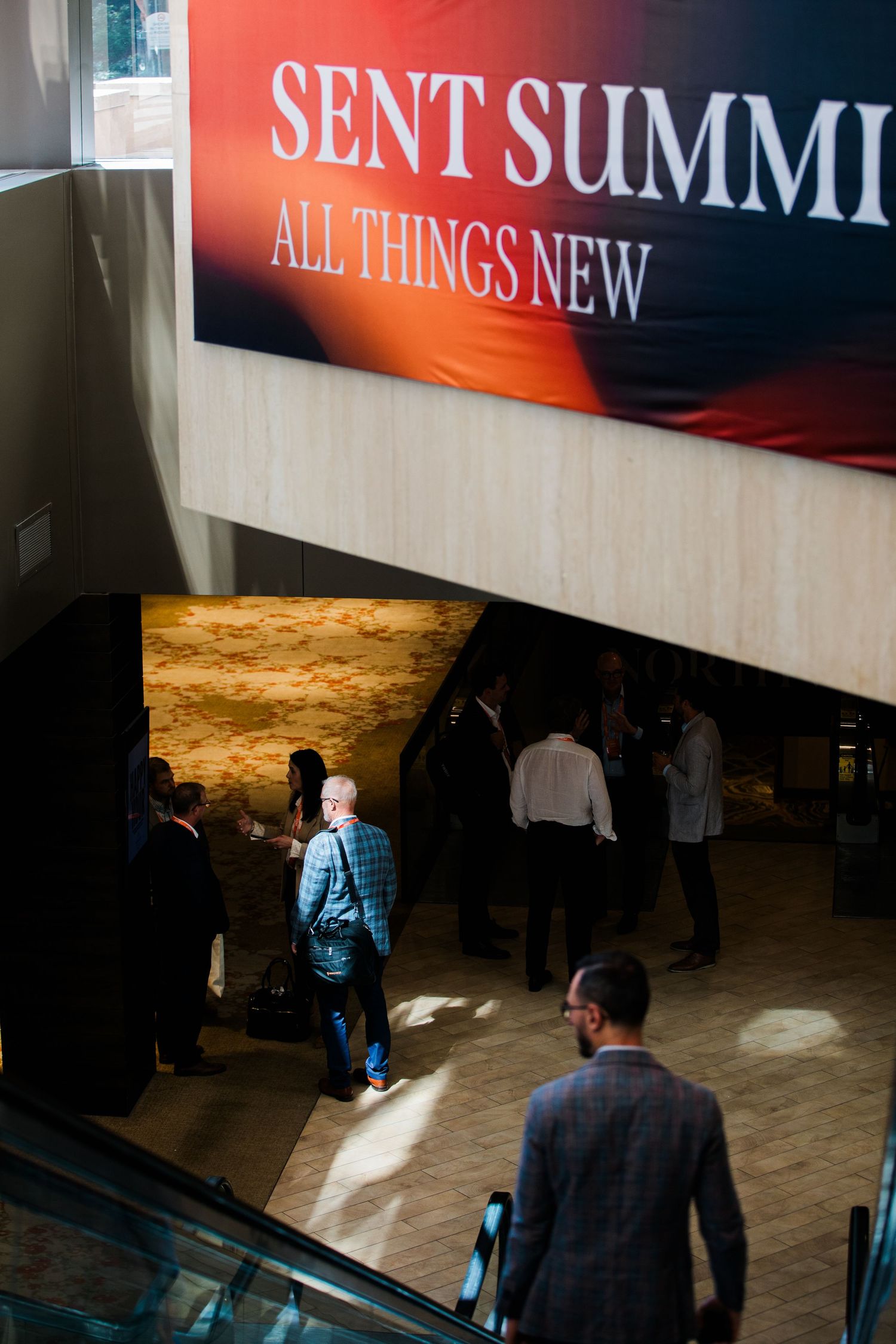 Attendees gather in a convention center lobby beneath a large red Sent Summit All Things New banner.