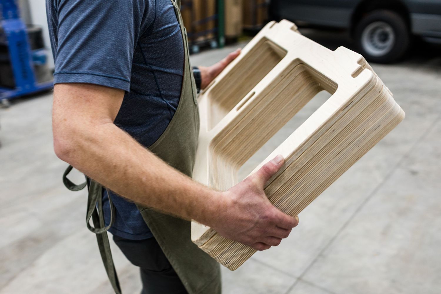 Person carrying stacks of wooden boxes or crates across a loading area.