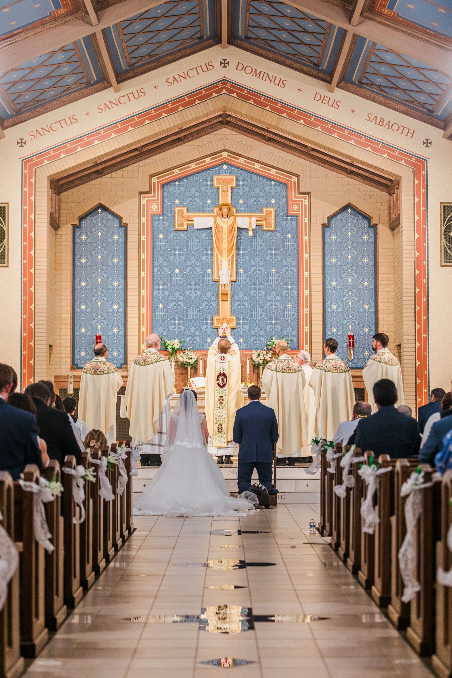 Bride and groom walk down the aisle of a decorated Catholic church during their wedding ceremony.