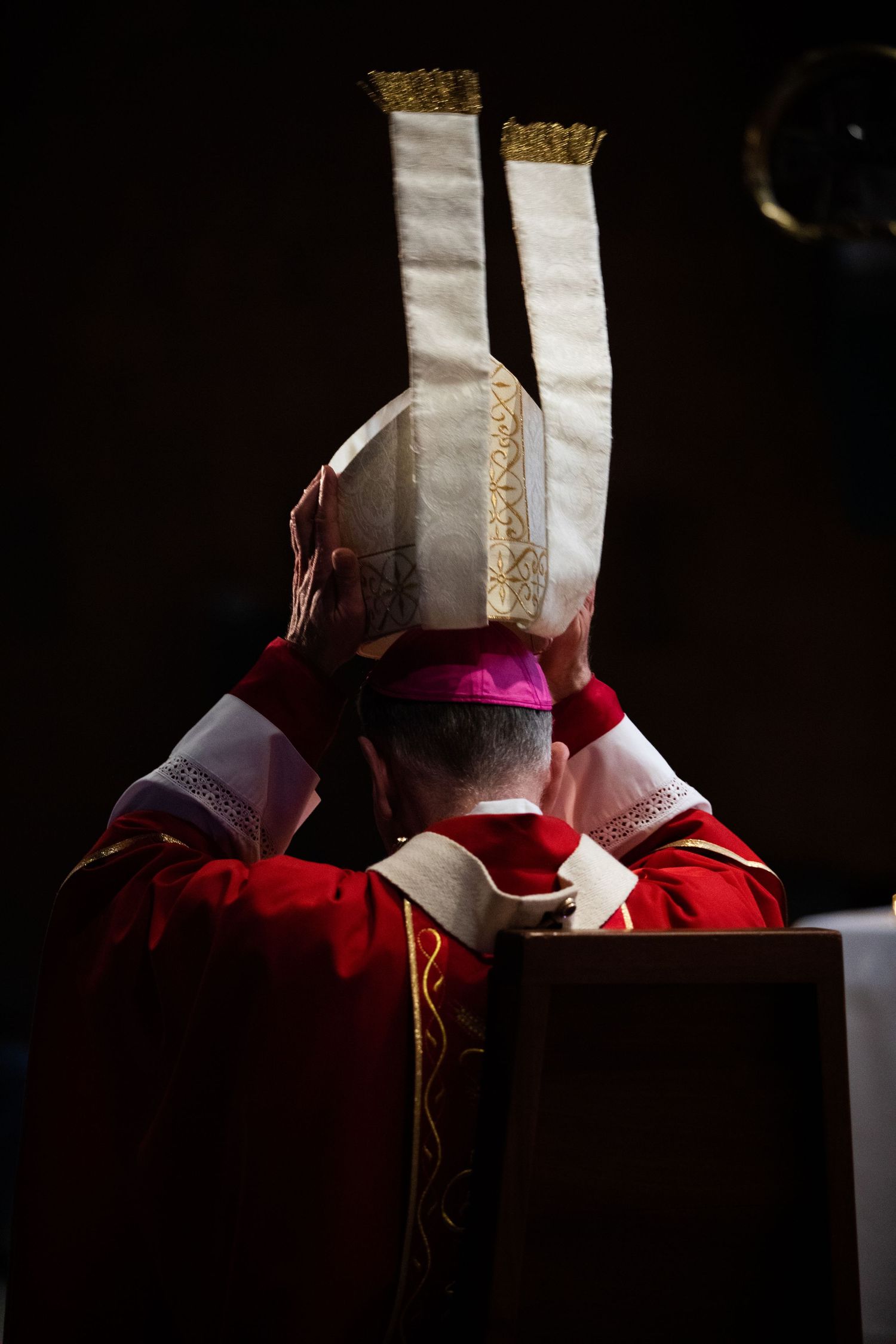 Traditional red and white religious vestments in dramatic lighting.