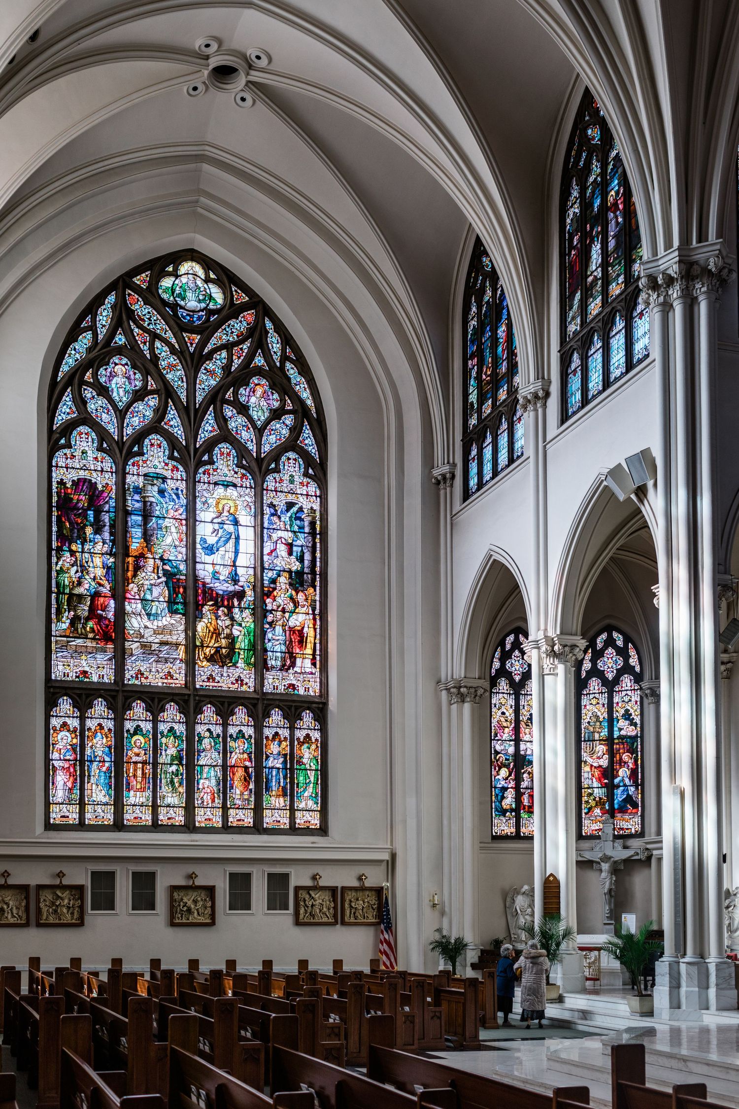 Gothic church interior with ornate stained glass windows and wooden pews.