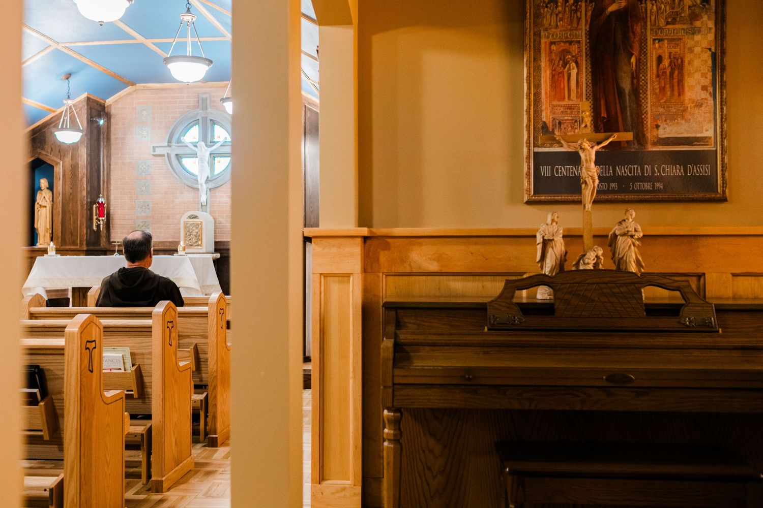 A peaceful Catholic church interior with wooden pews, stained glass, and religious statues on display.