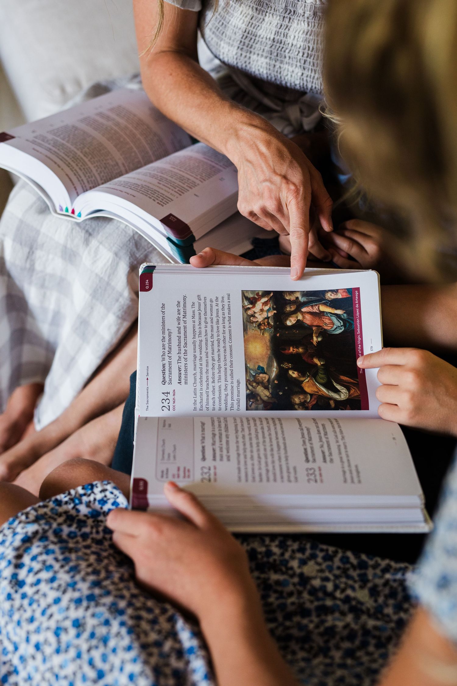 Two people reading and discussing illustrated religious books together, pointing at pages.