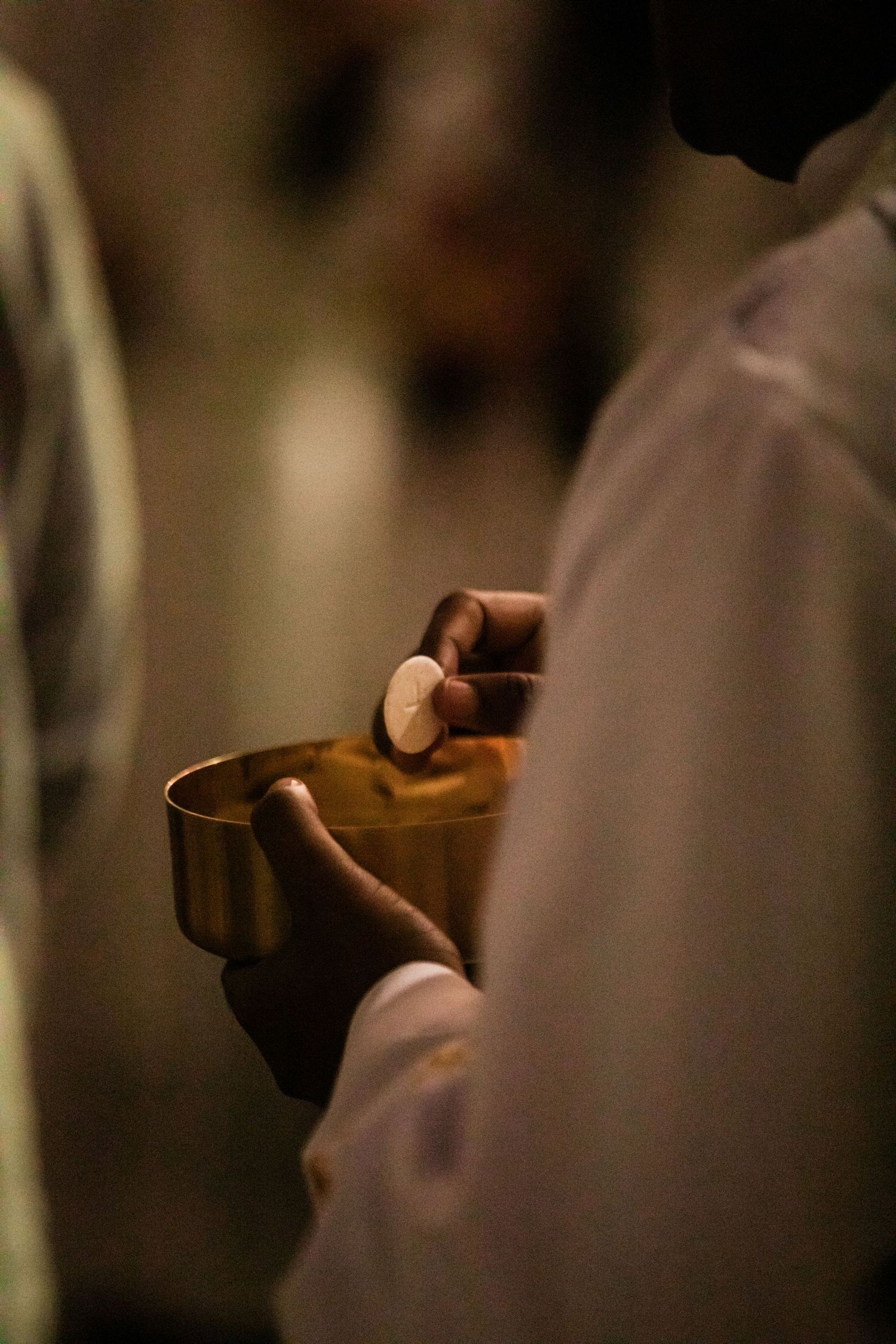 Close-up of hands holding a ceremonial vessel in dim lighting.