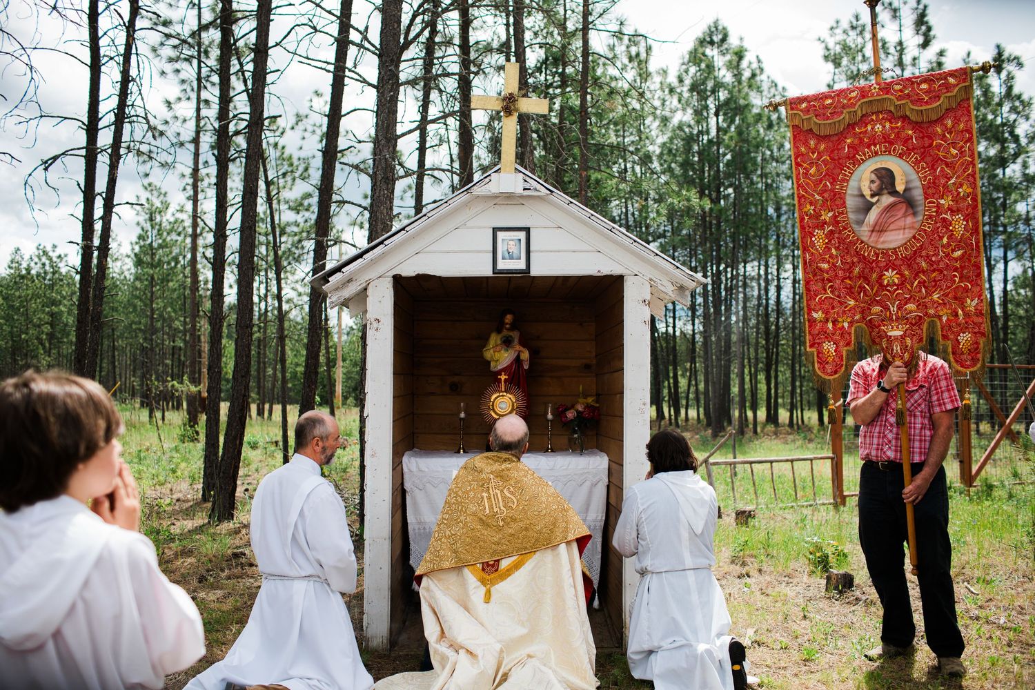 Wedding party poses in a wooded outdoor setting with red banners and decorative elements.