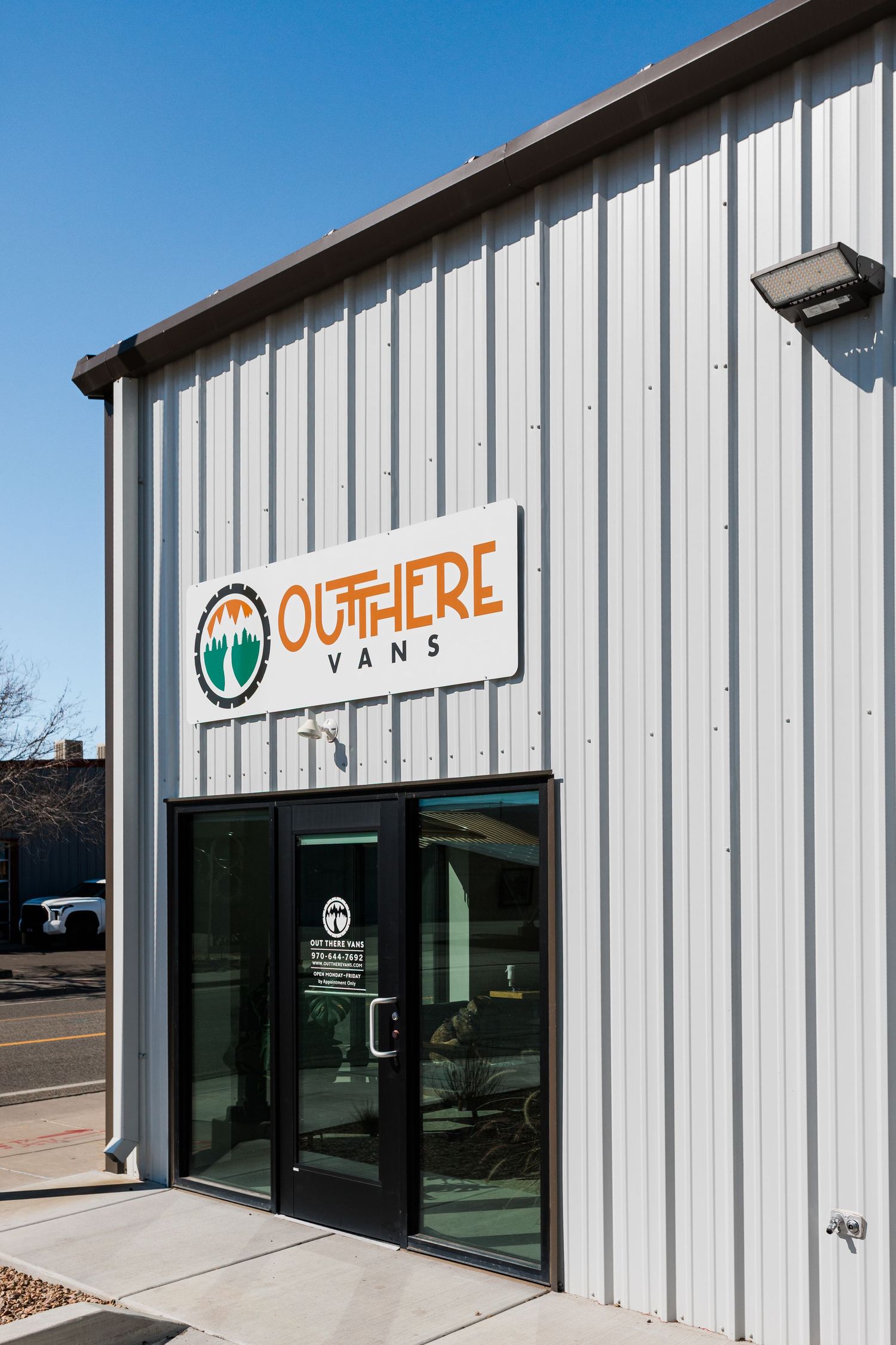 Out There Vans logo and storefront on a white metal building with glass doors under blue sky.