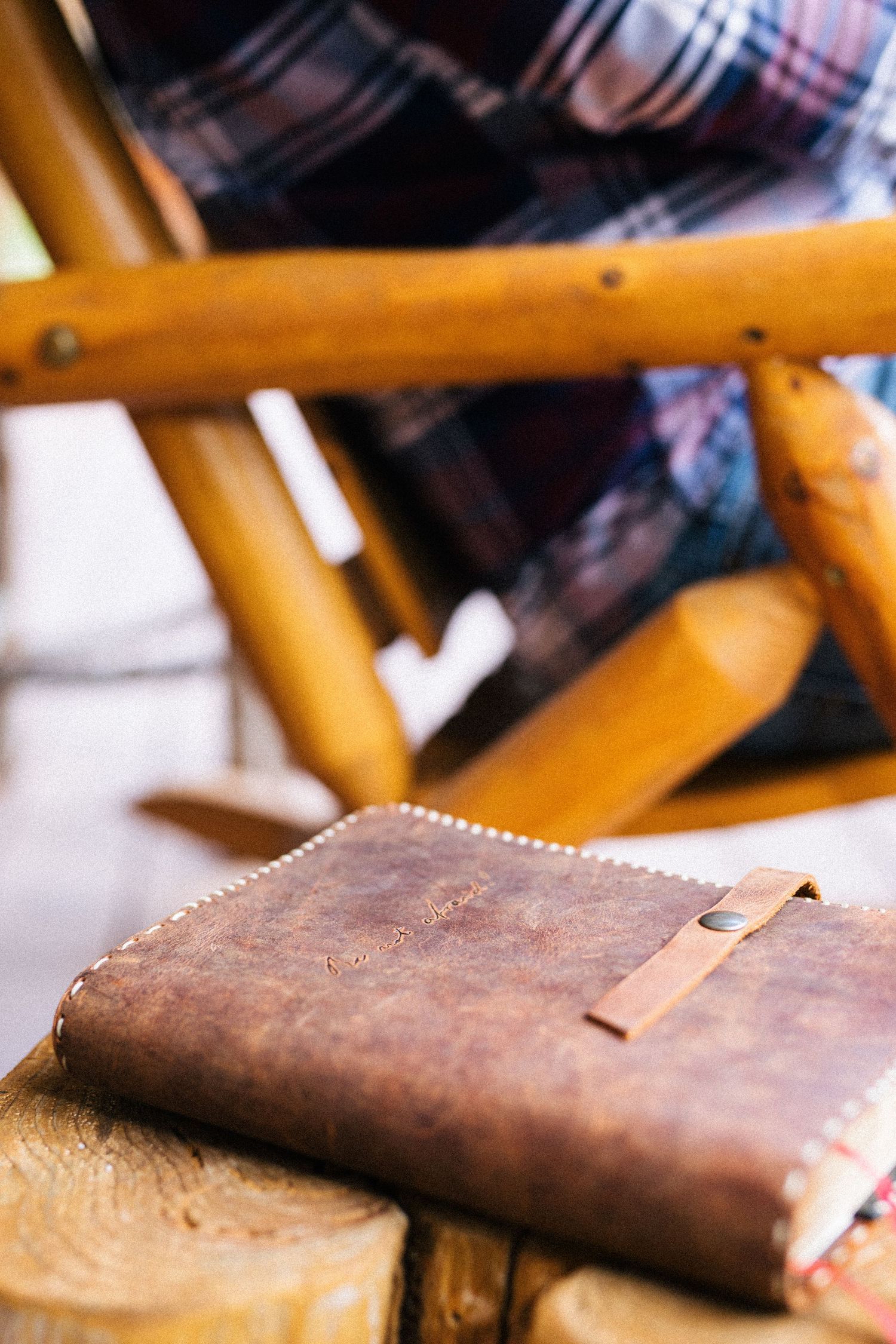 A vintage brown leather wallet rests against an orange metal chair frame in macro detail.