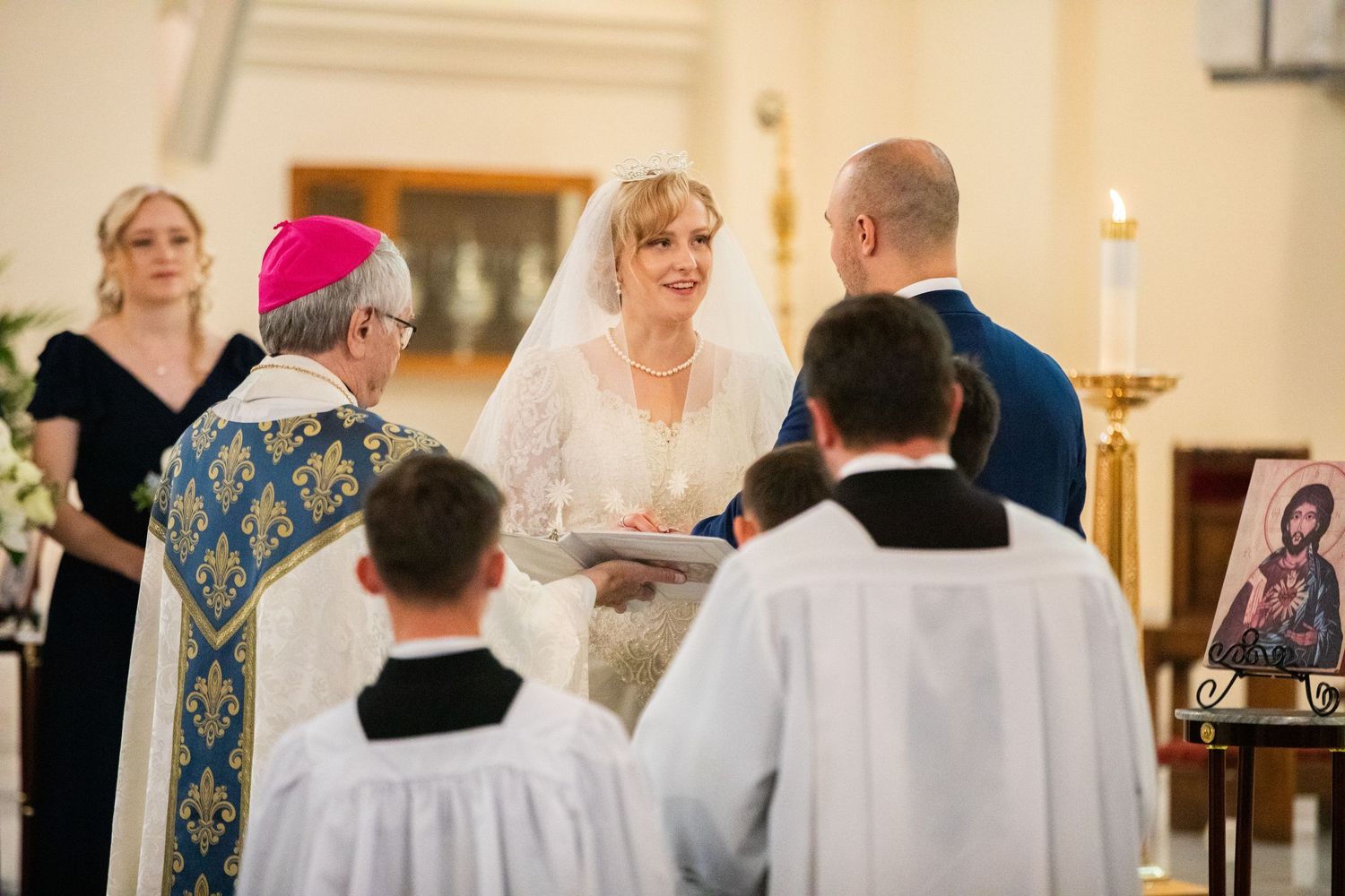 Bishop officiating elegant wedding ceremony with bride and groom exchanging vows at church altar.