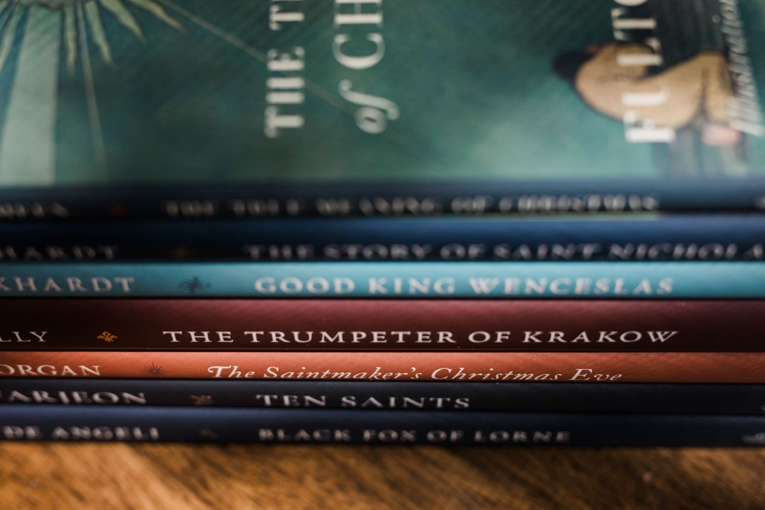 A row of hardcover book spines on a shelf showing various titles about saints and religious history.