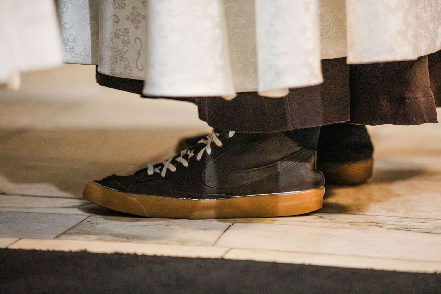 Brown leather shoes with white laces are displayed on a wooden floor surface.