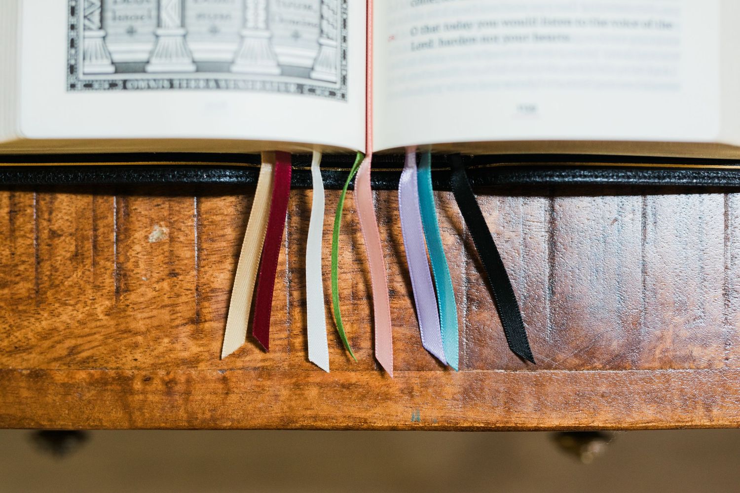 Open Liturgy of the Hours book displaying multiple colorful ribbon bookmarks hanging from the spine.