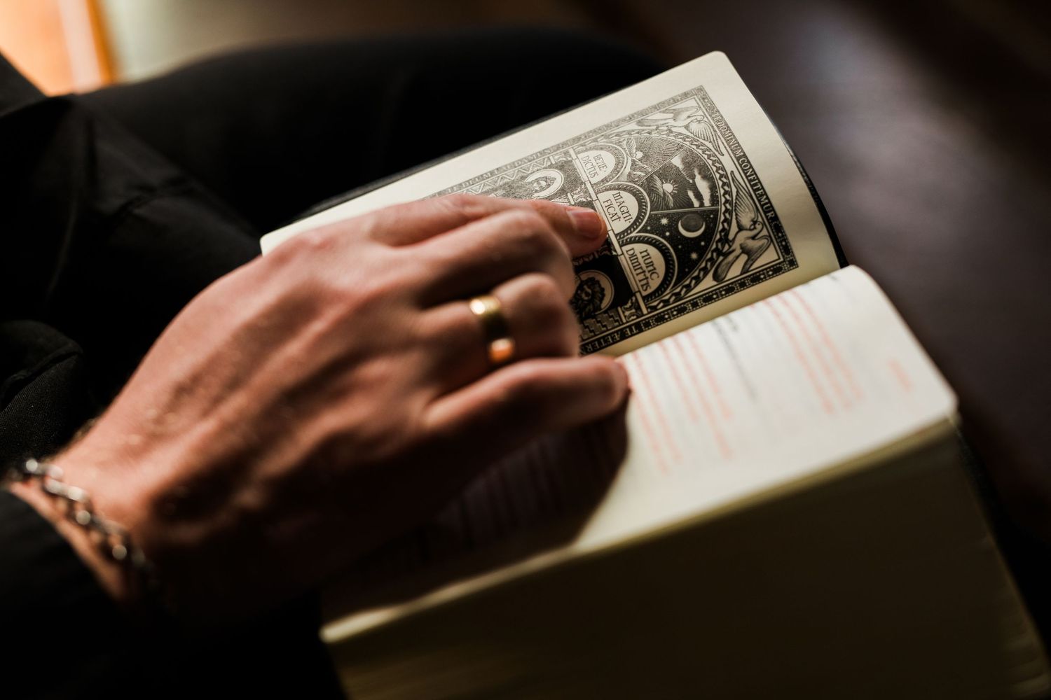 Close-up of hands holding an open religious liturgical book with decorative cover page.