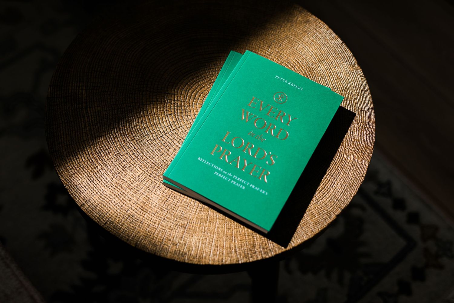 Two green hardcover books with gold embossed text resting on a woven chair.