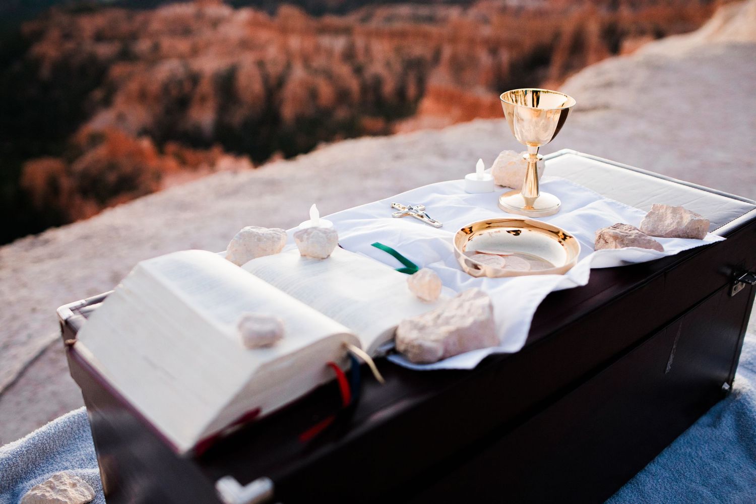 Religious communion elements and sacred items arranged on a table against a scenic mountain backdrop.