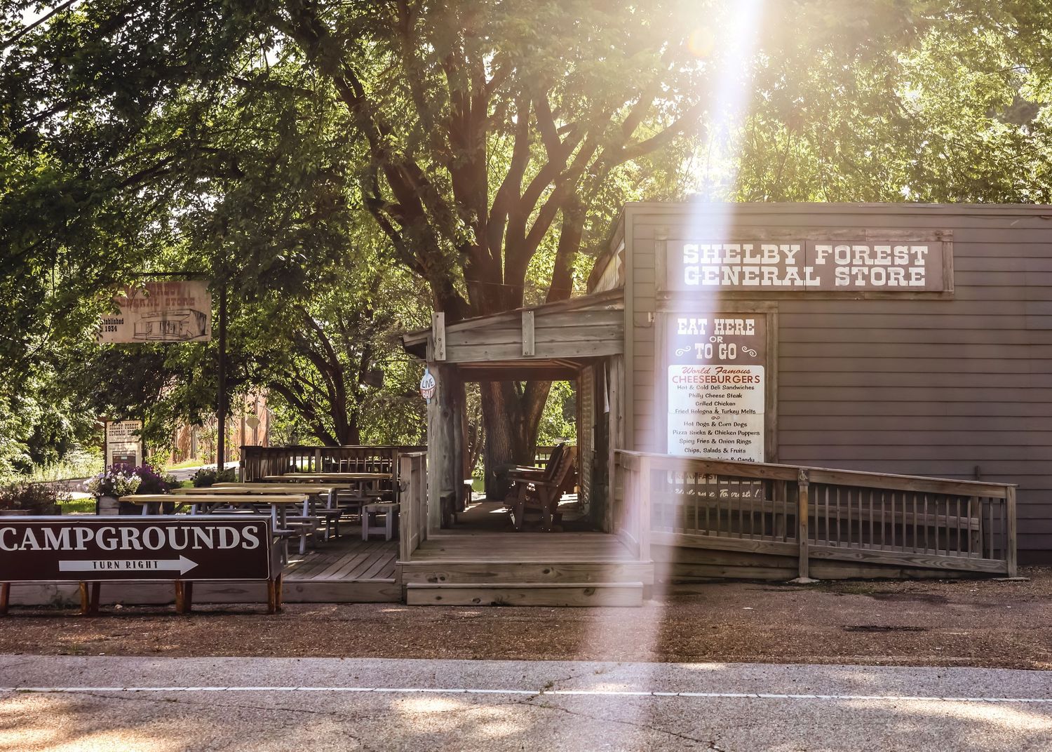 Rustic campground entrance with wooden building and sunbeam breaking through trees.