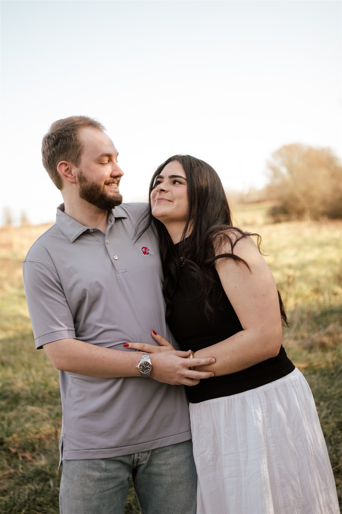 Couple in casual attire sharing intimate moments in outdoor setting during golden hour.