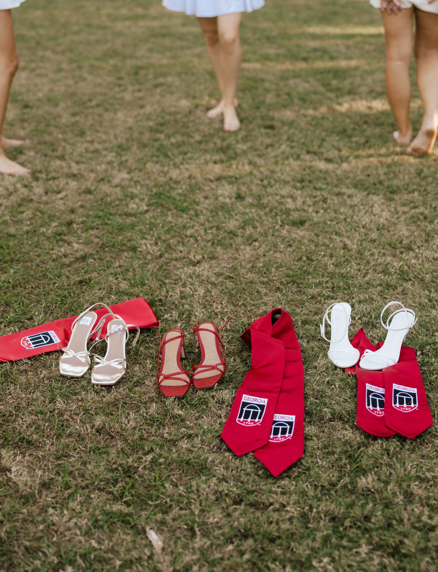 Red and white graduation stoles and accessories arranged on grass in a decorative layout.
