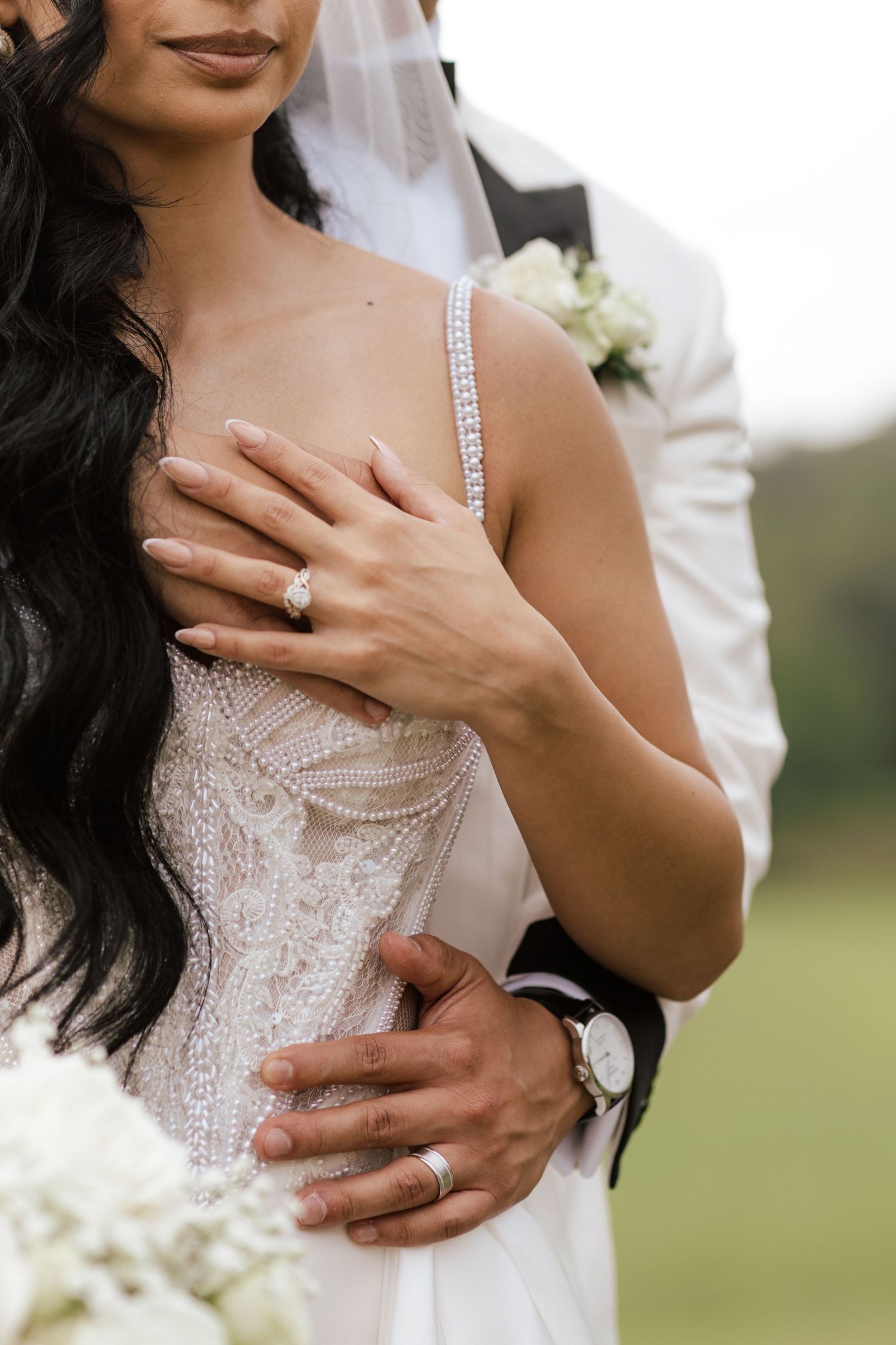 Close-up details of a bride's lace wedding dress and engagement ring.