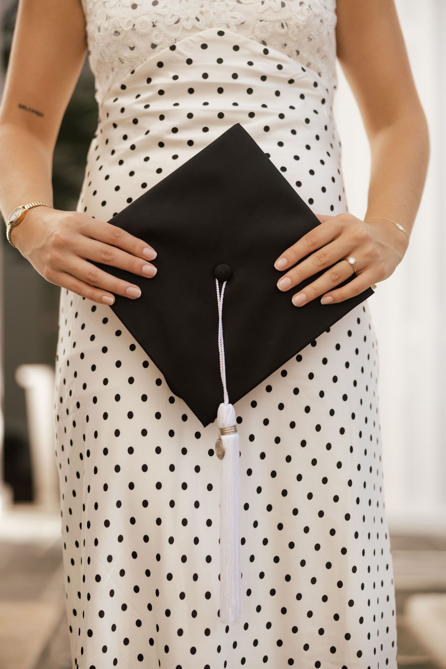 Close-up of polka dot dress with black graduation cap held against it.
