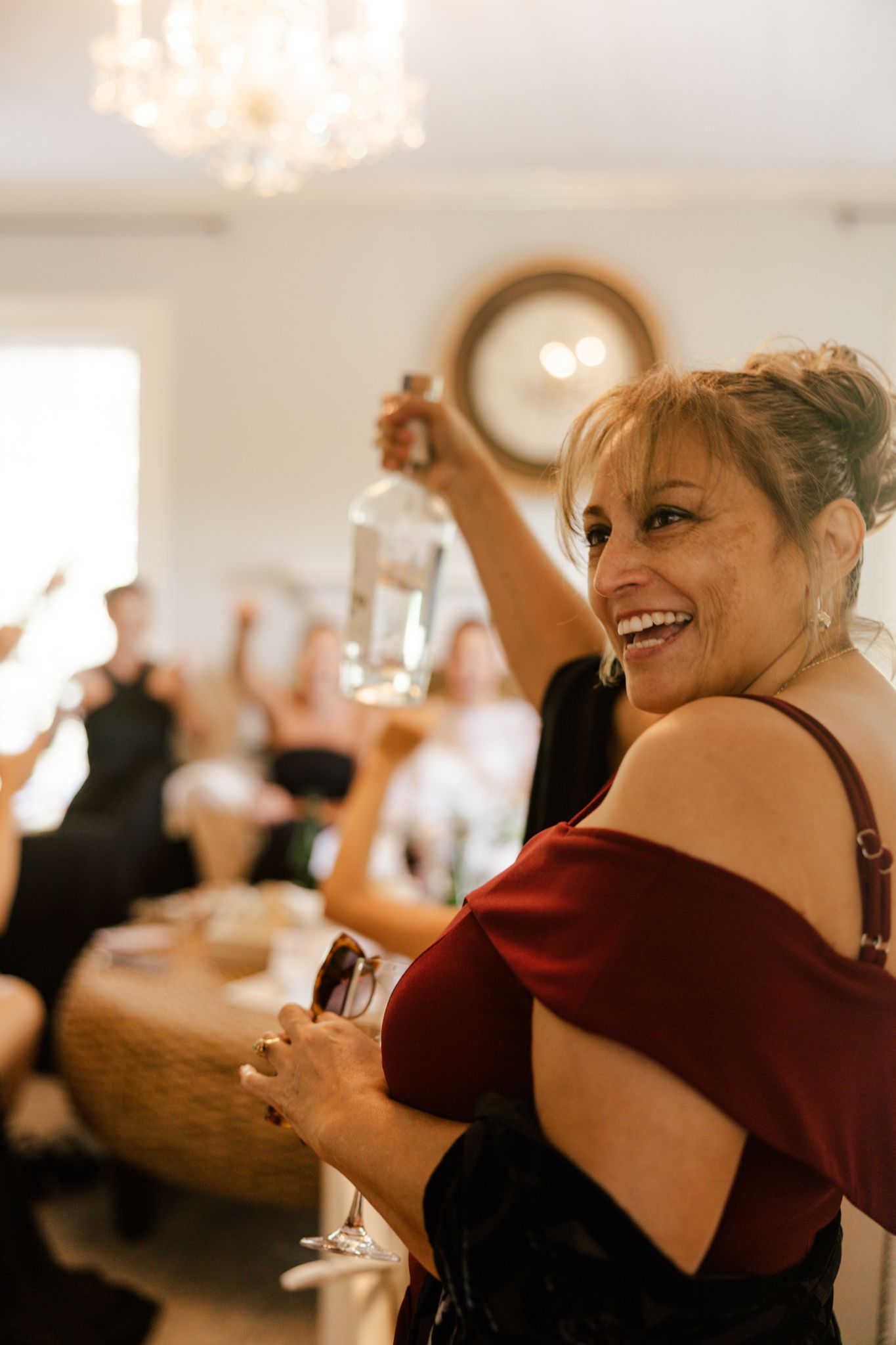 Wedding guests in formal attire raise their glasses in celebration at a reception.