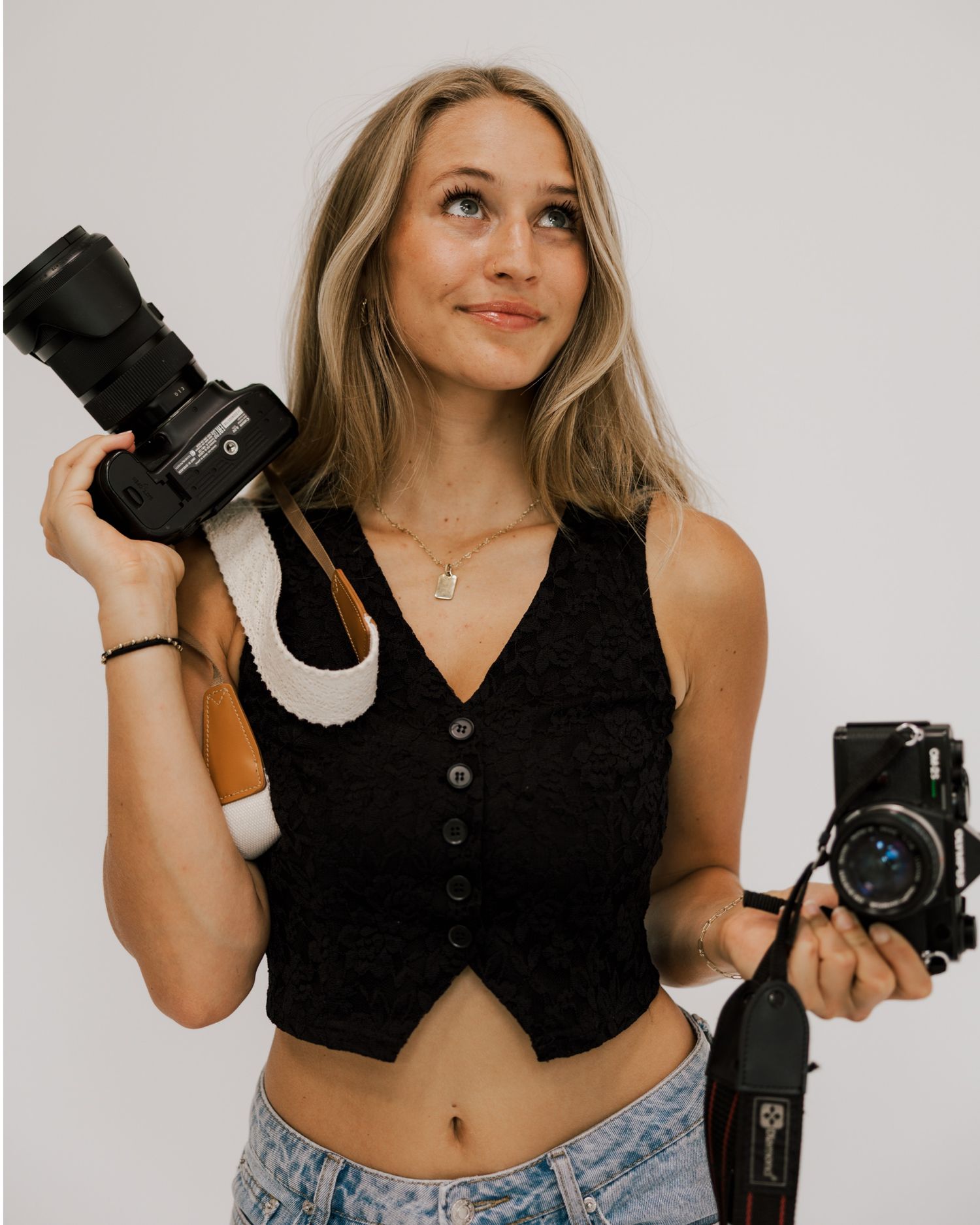 A photographer poses with professional cameras against white background.
