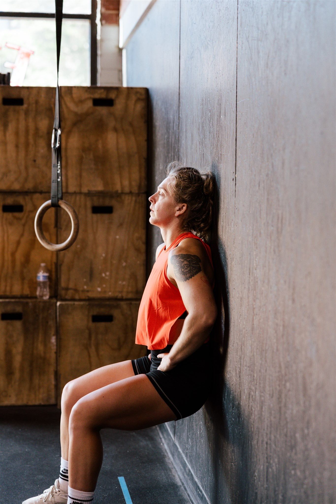 Athletic person doing wall sits during intense workout session in rustic gym setting.