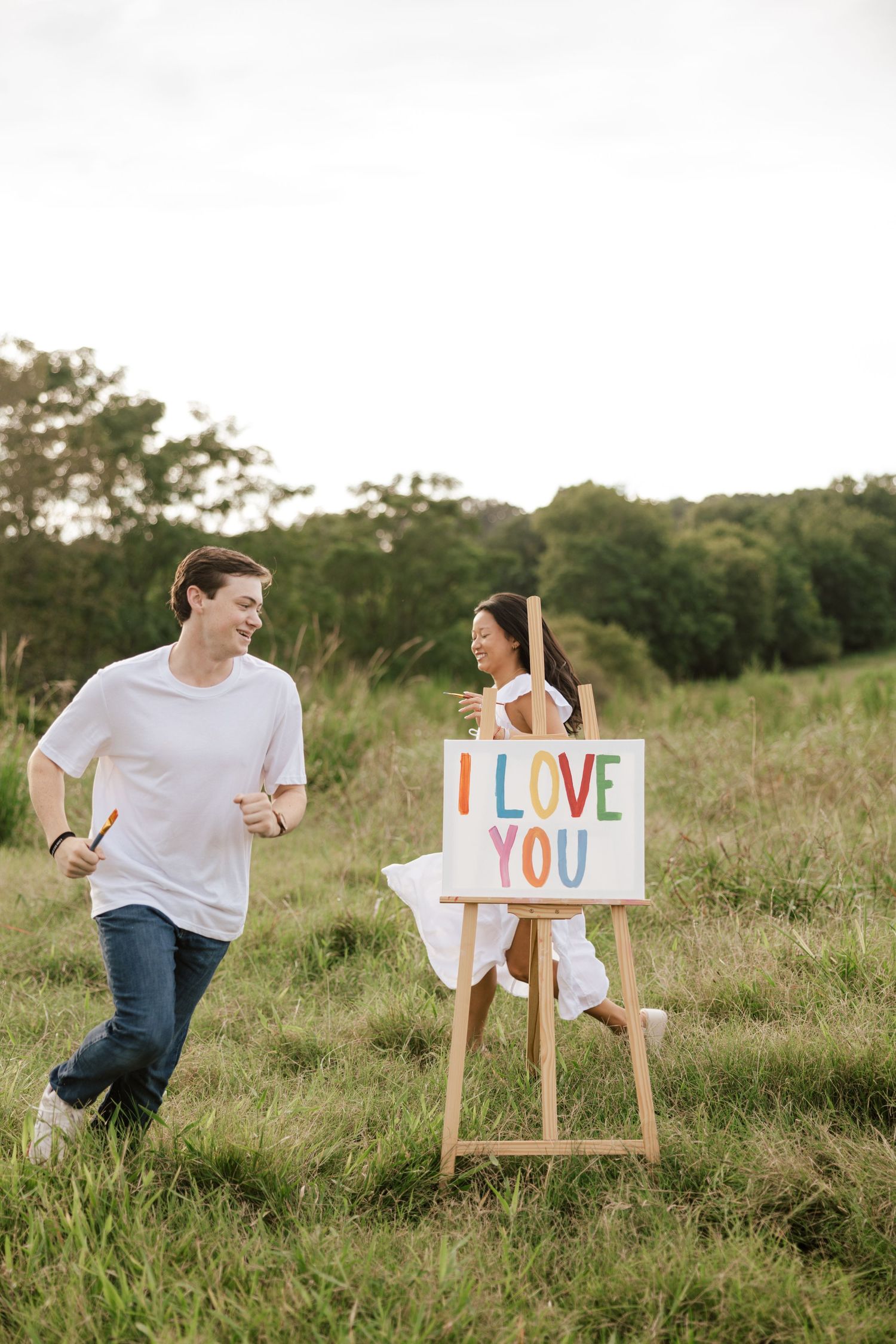 Playful outdoor photoshoot with white signs and easel in grassy field.