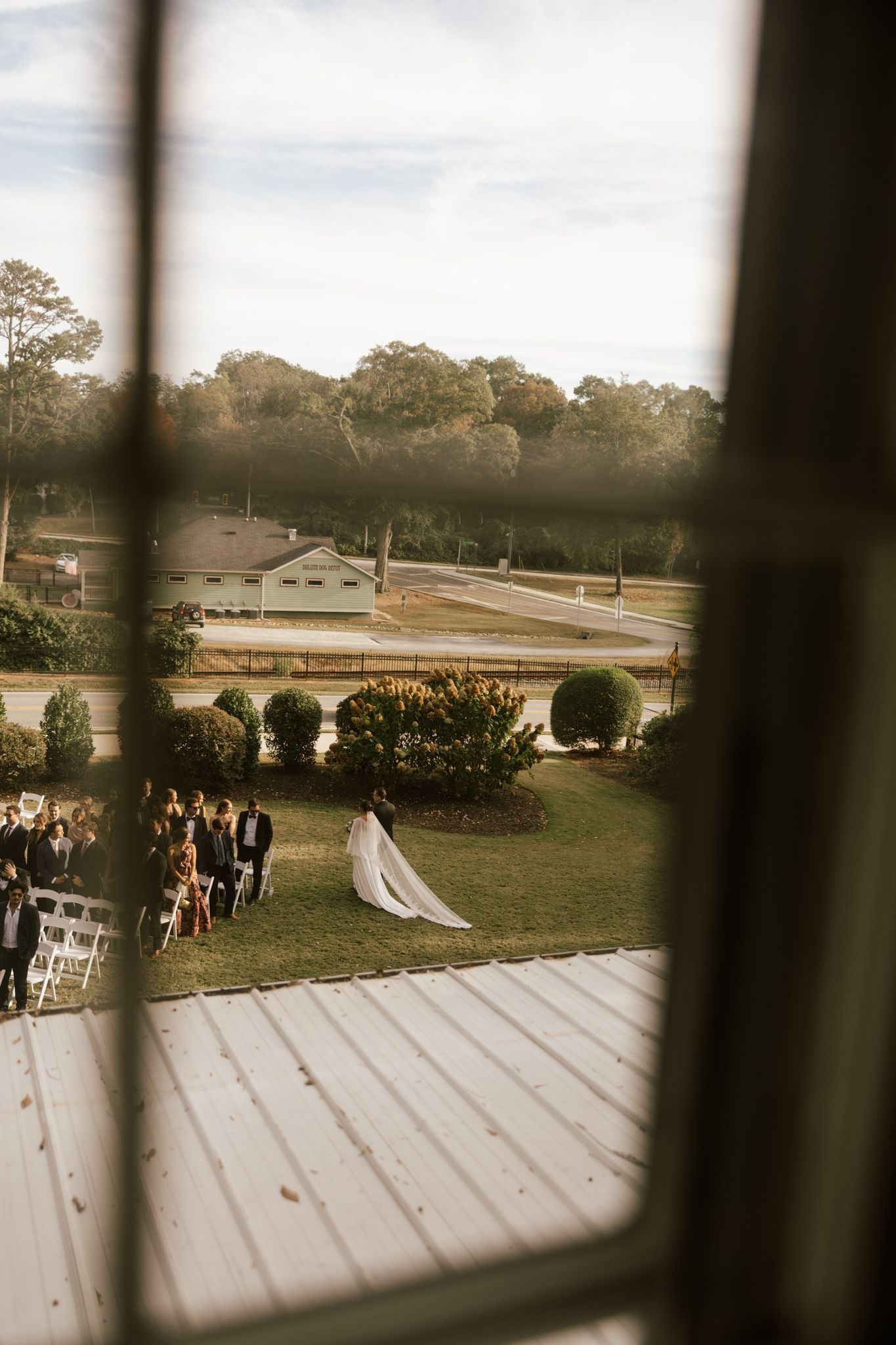 Aerial view of outdoor wedding ceremony through window frame.