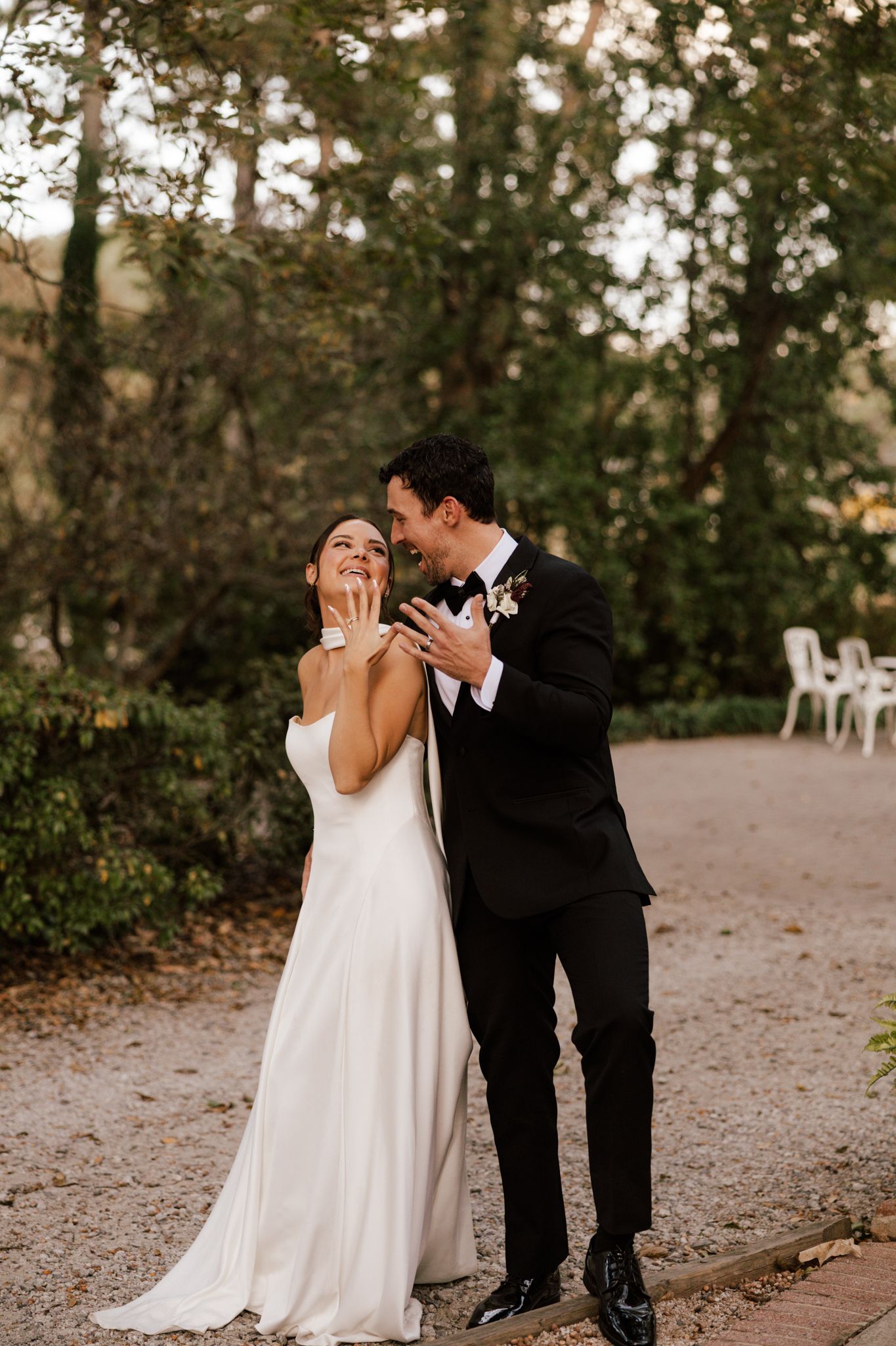 Couple in wedding attire sharing a joyful moment outdoors at sunset.