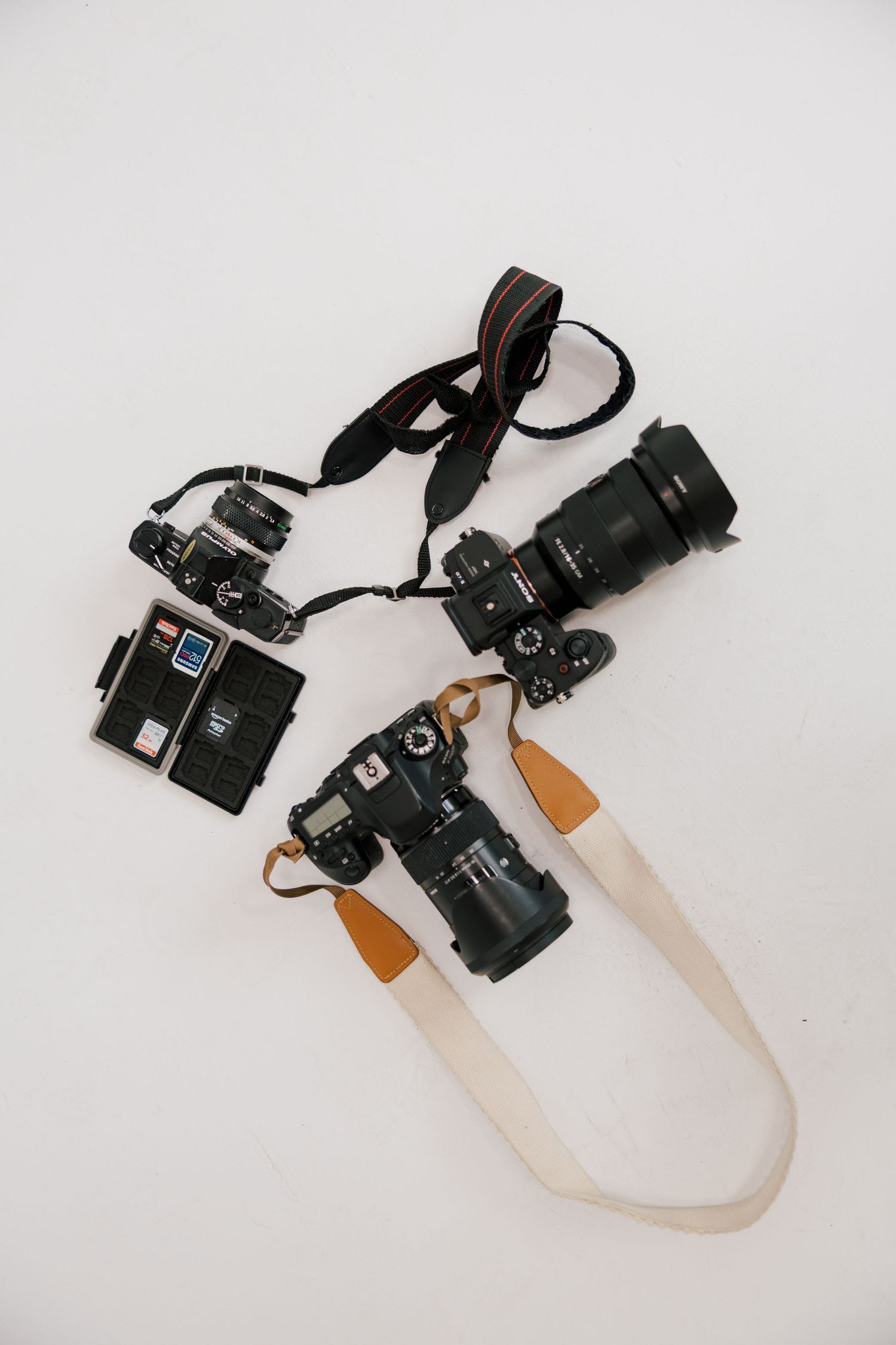 Collection of professional cameras with straps laid out on white surface.