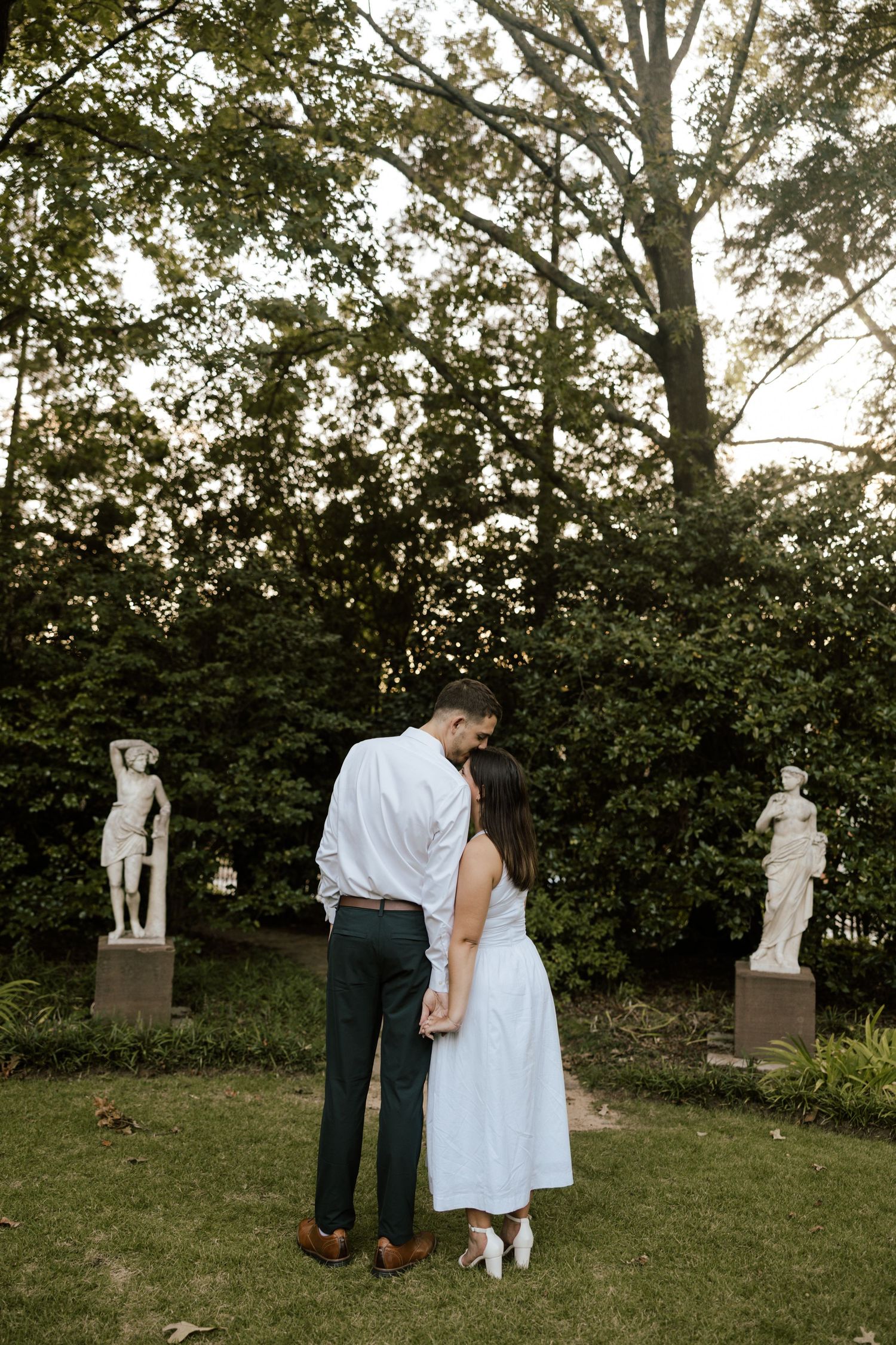 Outdoor garden wedding ceremony setup with white decor and natural greenery.