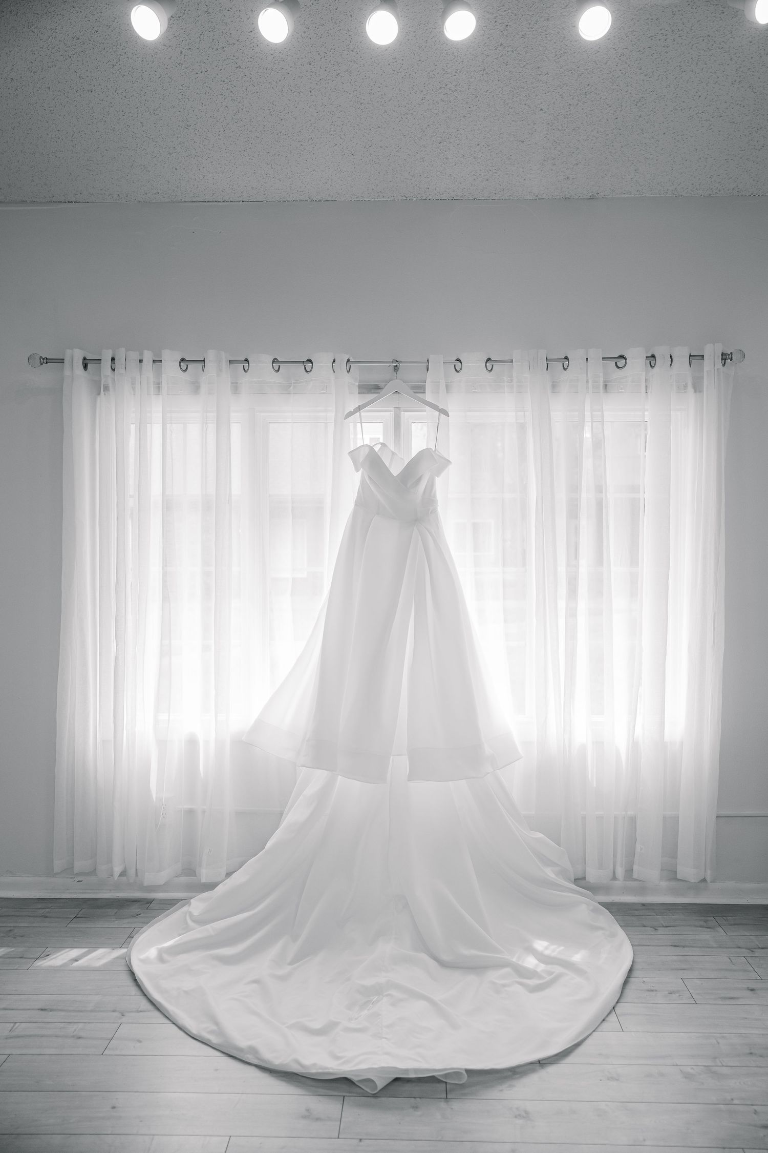 A sequence of elegant white wedding gowns displayed in a studio setting with soft lighting and sheer curtains.