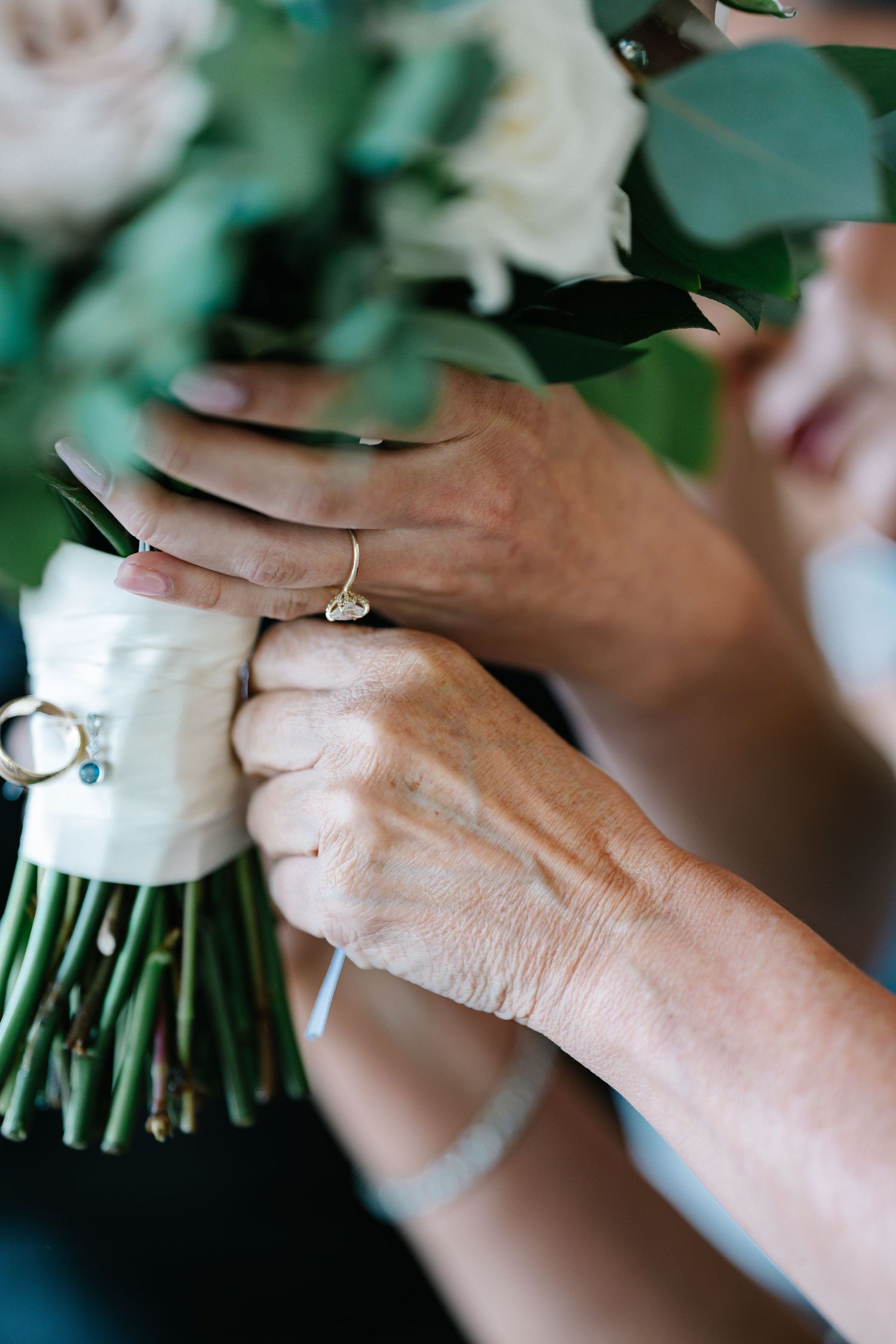 Close-up sequence of hands holding white floral bouquet with diamond engagement ring and wedding band.