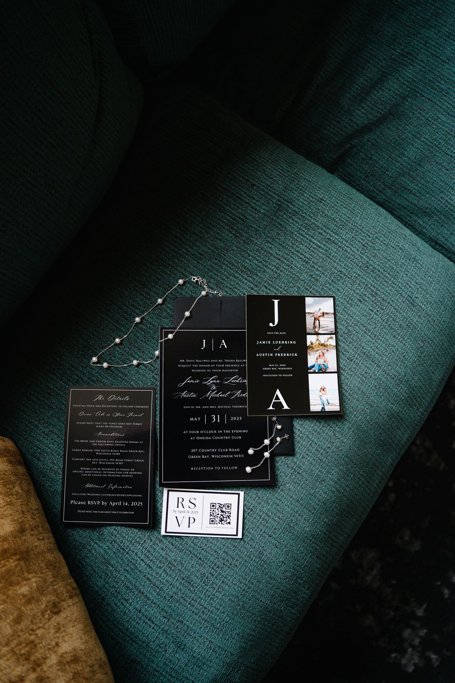 Modern black wedding invitations with monogram details laid out on teal velvet surface.
