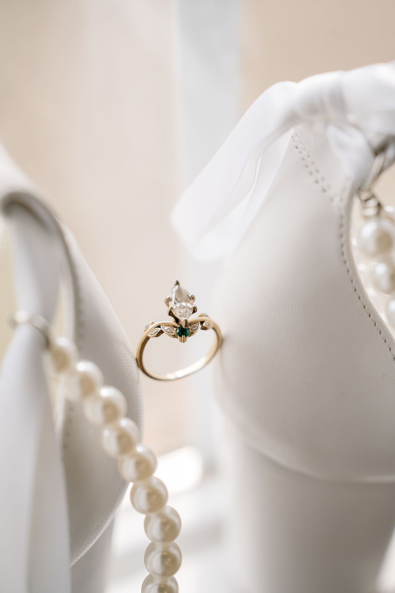 A delicate string of white pearls draped elegantly against a soft white background with a gold ring accent.
