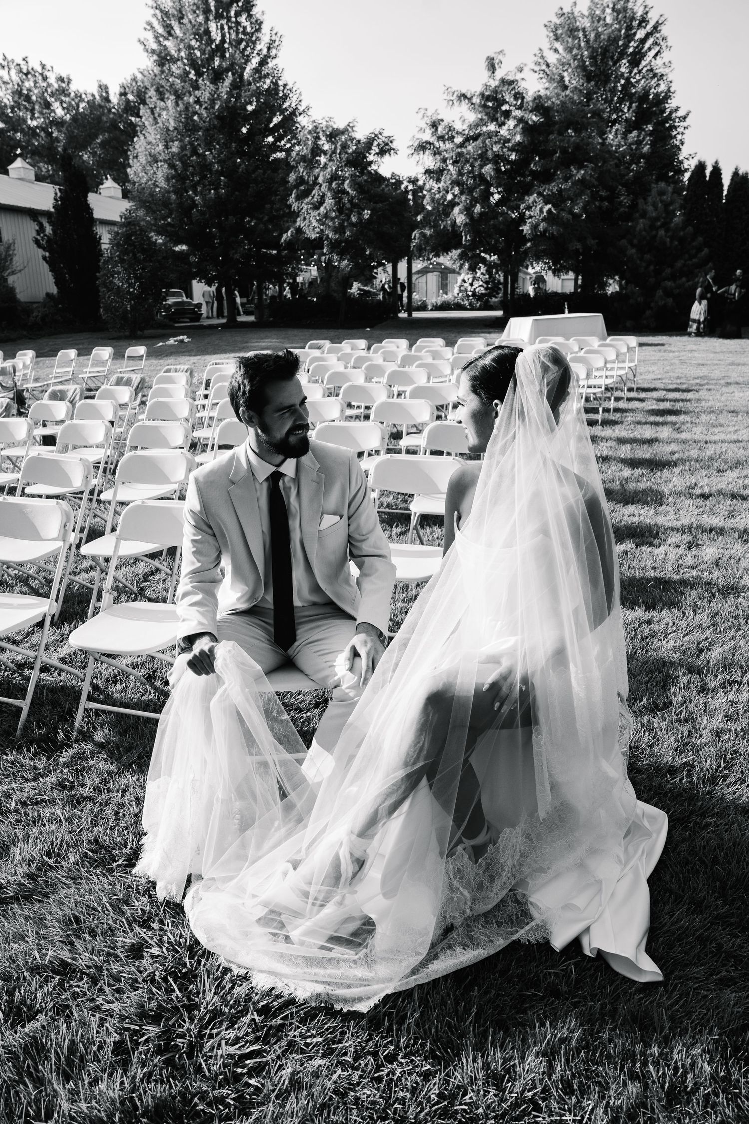 A black and white photo sequence showing a couple sitting on white chairs at an outdoor wedding ceremony.