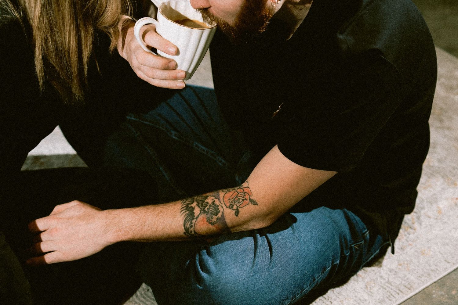Close-up shot of someone holding a cup of coffee in dark moody lighting.
