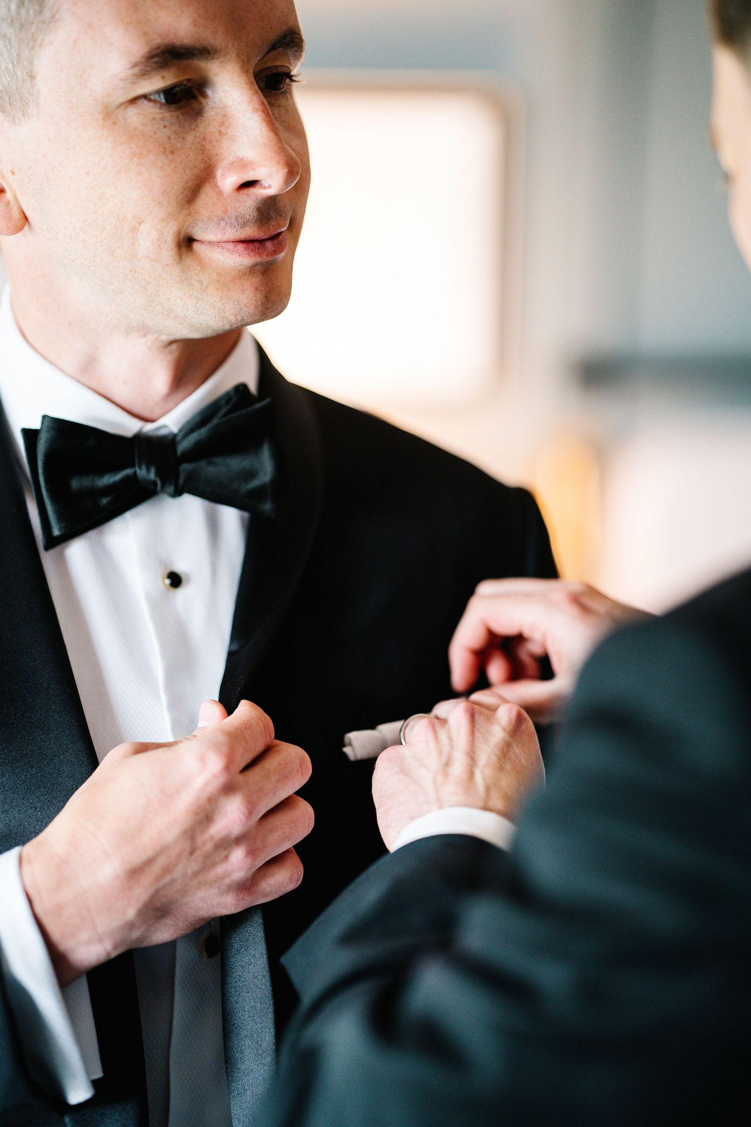 Close-up sequence of someone adjusting a black bow tie on a white dress shirt.