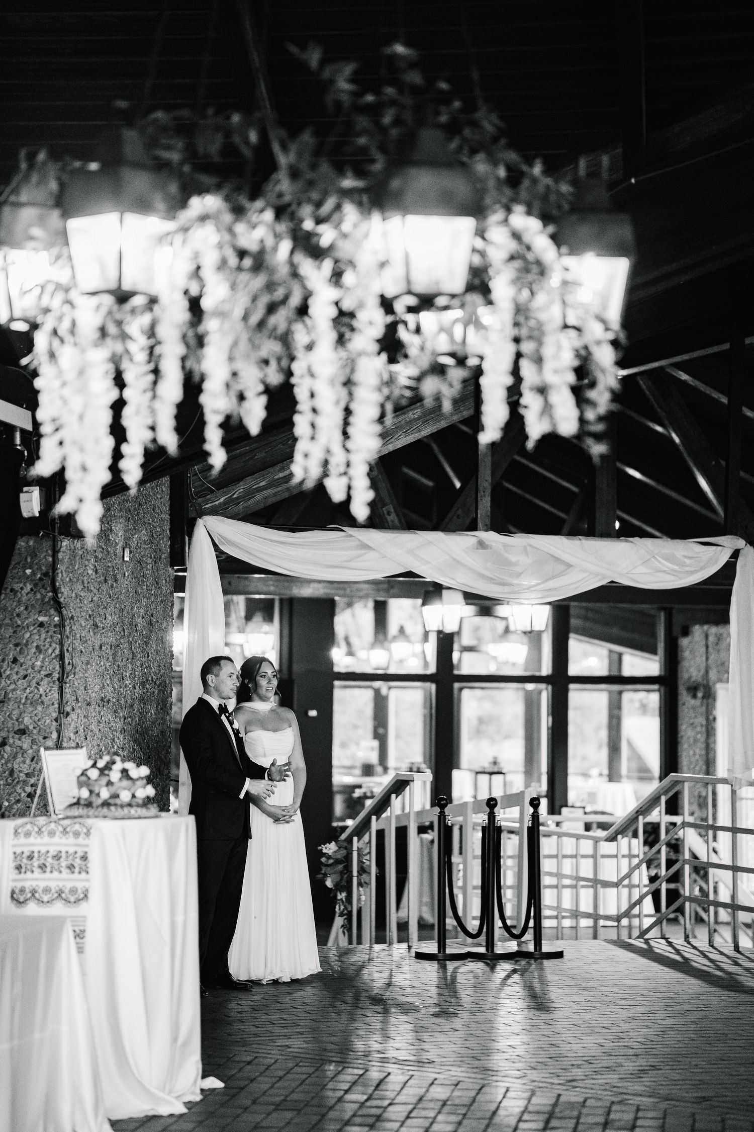 Romantic first dance at an outdoor wedding reception under hanging white floral decorations and string lights.